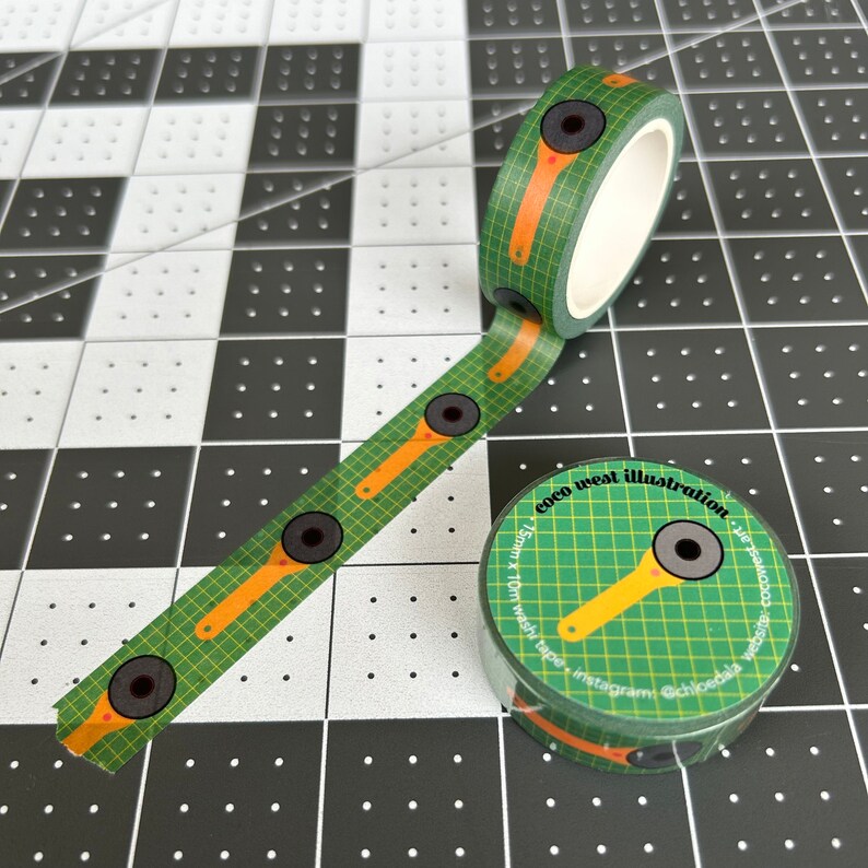May include: Green washi tape with a grid pattern and orange accents, featuring a repeating design of black circles and yellow shapes. The tape roll displays the text "coco west illustration".
