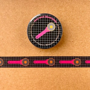 May include: A black and white round button and washi tape featuring a pink rotary cutter design. The button has the text "coco west illustration" and social media handles. The washi tape has a repeating pattern of the same cutter design.
