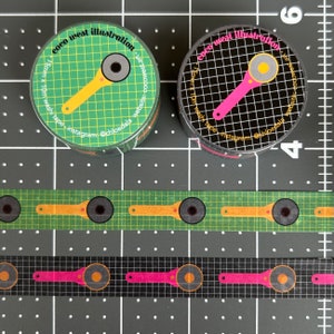 May include: Two rolls of washi tape with a rotary cutter design, one on a green grid and the other on a black grid. The tape is 15mm x 10m. The text "coco west illustration" and Instagram handle are visible.