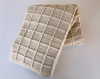 May include: A beige crocheted throw blanket with a square pattern.