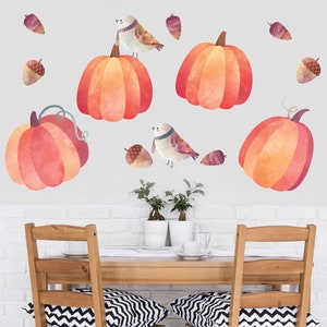 May include: A set of watercolor-style pumpkin and bird wall decals. The decals feature orange pumpkins with green stems and brown acorns. There are also two birds with brown wings and white bellies. The decals are perfect for adding a touch of fall to any room.