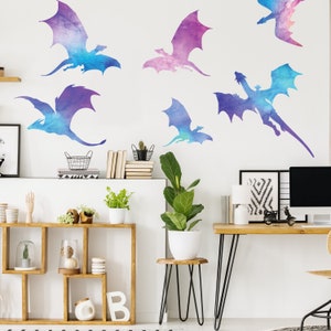 May include: A white wall with six watercolor dragon decals in shades of purple, blue, and pink. The decals are arranged in a random pattern on the wall.