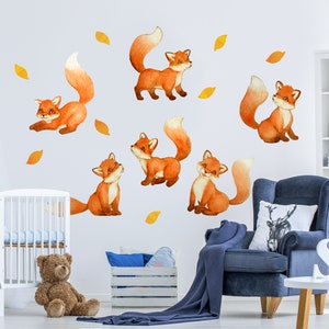 May include: A nursery wall decorated with six orange fox animal wall decals. The decals are arranged in a playful pattern on a white wall. The decals are perfect for a child's room or playroom.