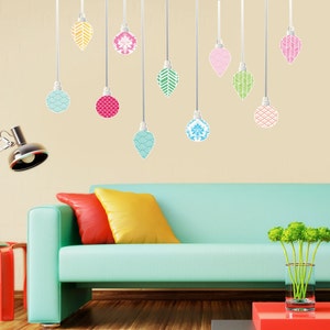 May include: A teal blue sofa with two pillows, one red and one yellow, sits in front of a wall with decorative Christmas ornament stickers. The ornaments are various colors and patterns, including blue, green, pink, and yellow.