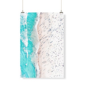 May include: An aerial view of a beach with turquoise water and white sand. The beach is crowded with people, and their shadows are visible on the sand.