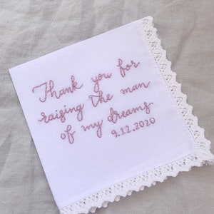 Image shows a white handkerchief with a detailed edge, folded into quarters. The text is the standard message for this listing, with a date added on, in pink thread.