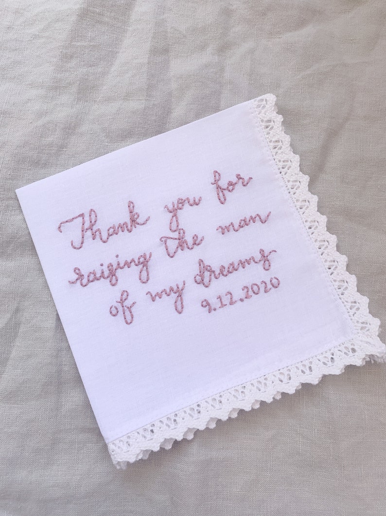 Image shows a white handkerchief with a detailed edge, folded into quarters. The text is the standard message for this listing, with a date added on, in pink thread.