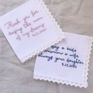 Image shows a white handkerchief with a detailed edge, folded into quarters. The text is the standard message for this listing, with a date added on, in pink thread. Another hankie from a different listing is also in the photo.
