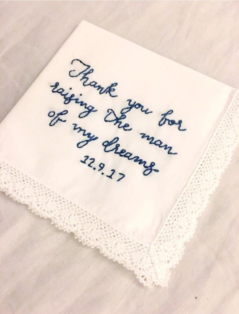 Image shows a white handkerchief with a detailed edge, folded into quarters. The text is the standard message for this listing, with a date added on, in blue thread.