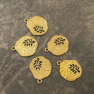 May include: Five gold-toned metal charms with a leaf design. Each charm has a loop for attaching to a necklace or bracelet.