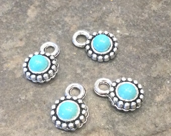 May include: Four silver charm pendants with turquoise blue stones. Each pendant has a small loop at the top for attaching to a necklace or bracelet.