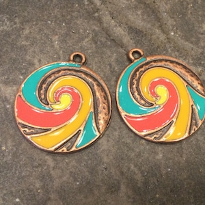 May include: Two round copper charms with a swirl design in red, yellow, and teal enamel.