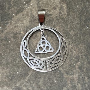 May include: A silver pendant with a Celtic knot design. The knot is in the shape of a triangle and is surrounded by a circle of smaller knots.