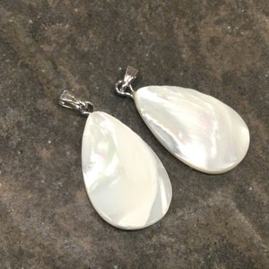 May include: Two white pearlescent teardrop-shaped pendants with silver jump rings.