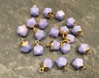 May include: A collection of 18 purple and gold geometric shaped charms with a gold loop for hanging.