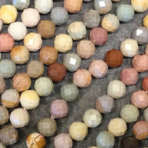 May include: A strand of colorful faceted gemstone beads. The beads are various shades of brown, pink, green, and yellow. The beads are all round and have a faceted finish.
