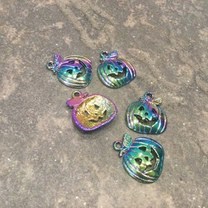 Pu&ograve; includere: Cinque ciondoli a forma di zucca in metallo iridescente con facce di jack-o'-lantern. I ciondoli sono un mix di verde, blu e viola.