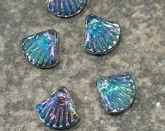 May include: Five iridescent seashell-shaped beads. The beads have a translucent, shimmering quality with colors ranging from blue to purple. The shells have a ridged texture.