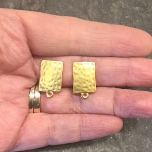May include: Two gold-toned metal earring blanks with a hammered texture and a jump ring at the top.