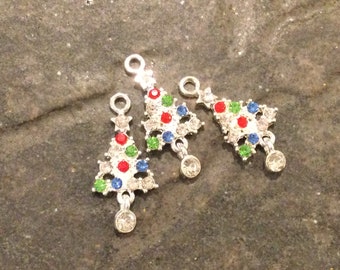 May include: Three silver Christmas tree charms with red, green, and blue rhinestones. Each charm has a loop at the top for hanging and a dangling rhinestone at the bottom.