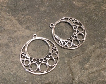 May include: Two silver-toned metal earring charms with a circular design featuring a large circle with smaller circles around it.