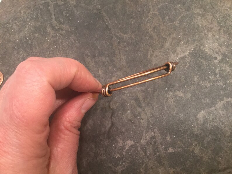 May include: A simple copper wire bracelet with a double-loop closure.