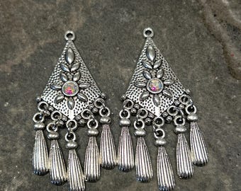 May include: A pair of silver dangle earrings with a triangular design and iridescent rhinestones. Each earring has a fringe of silver tassels.