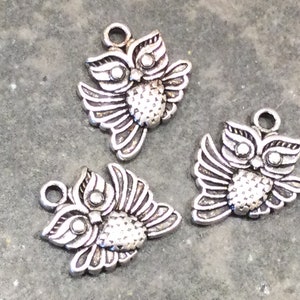 May include: Three silver owl charms with detailed wings and beady eyes. The charms have a loop at the top for attaching to jewelry or other crafts.