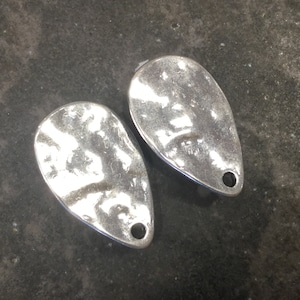 May include: Two silver teardrop-shaped pendants with a hammered texture and a small hole at the top.