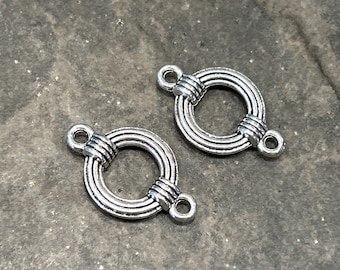 May include: Two silver-toned metal connector charms with a circular design. Each charm has a loop on either side and a decorative, twisted, circular design in the center.