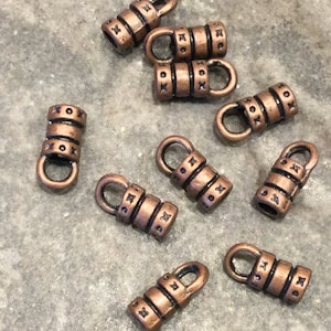 May include: Ten copper-colored metal cord end caps with a small loop at the top and the word "XOX" engraved on each.