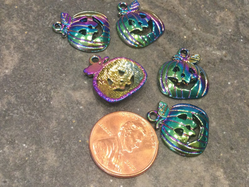 Pu&ograve; includere: Sei ciondoli a forma di zucca in metallo iridescente arcobaleno con facce di jack-o'-lantern. I ciondoli sono circa delle dimensioni di una moneta da un centesimo di euro.