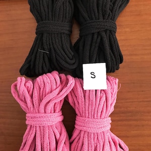 May include: Two bundles of black cotton cord and two bundles of pink cotton cord. The bundles are tied together with a white tag that says "S".