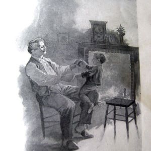 May include: Black and white illustration of a man seated in a chair, holding the hands of a child standing on his lap. A small stool is to the right. A fireplace and clock are in the background.