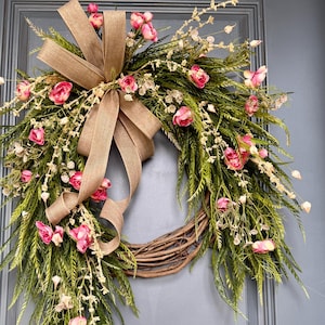 K&ouml;nnte beinhalten: Ein Kranz aus braunen Ranken mit einer Schleife aus Sackleinen und rosa Bl&uuml;ten. Der Kranz ist mit Gr&uuml;n und kleinen wei&szlig;en Bl&uuml;ten verziert.
