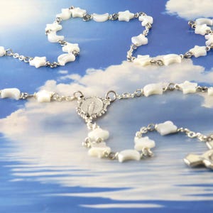 May include: A white ceramic mug with a black handle and the text "But First, Coffee" in a black, bold font. The mug is on a white surface.