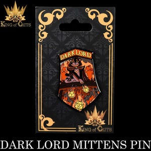 Puede incluir: Un pin de esmalte negro con un gato que lleva un sombrero y una t&uacute;nica de mago, sosteniendo un dado brillante. El gato est&aacute; sentado en un trono con llamas y dados. El pin dice "Dark Lord" en la parte superior y "King of Crits" en la parte inferior.