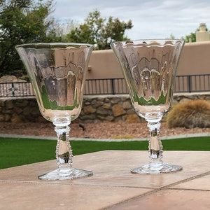 May include: Two clear glass wine glasses with a beaded stem and a fluted bowl.