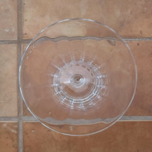 May include: A clear glass wine goblet with a fluted design. The goblet is empty and has a round base.