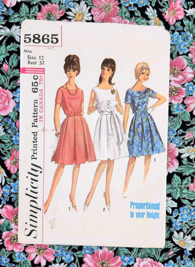 May include: Vintage Simplicity sewing pattern number 5865 for a dress. The pattern is for a miss, size 12, bust 32. The pattern includes three different dress styles, one in pink, one in white, and one in blue. The pattern is labeled "Proportioned to your Height".