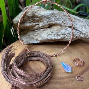 May include: Copper wire wrapped around a wooden base, with a copper wire circle, a crystal pendant, and copper wire rings.