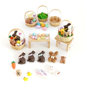 May include: An assortment of miniature Easter decorations, including woven baskets filled with toy bunnies, teddy bears, and eggs. Additional items include chocolate bunnies, a carrot, and colorful candies. The scene is set on a white background.