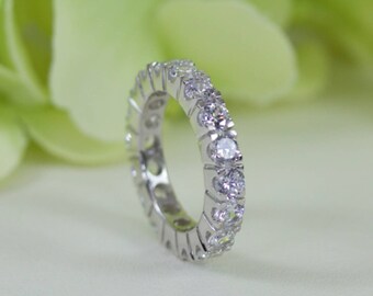 May include: A silver eternity band with a row of clear round cubic zirconia stones.