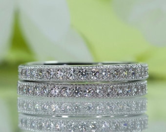 May include: Two silver eternity bands with a row of small, clear cubic zirconia stones set in a pave setting.