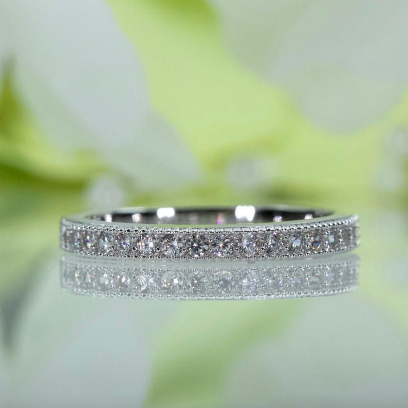May include: A silver band with a row of small, clear diamonds set in a milgrain design.