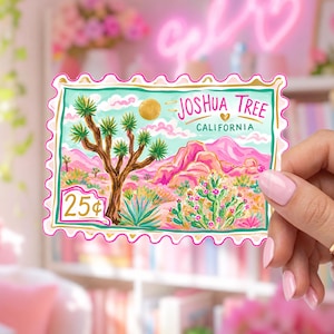 Puede incluir: Una pegatina rectangular con forma de sello postal que presenta una colorida ilustración del paisaje desértico de Joshua Tree. El diseño incluye un gran árbol de Josué, montañas rosas, cactus, un sol dorado y el texto Joshua Tree California 25¢.