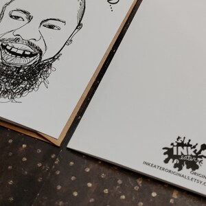 May include: Two greeting cards with a black and white line drawing of a smiling face with a beard. The cards are on a brown surface. One card has the drawing, the other has a logo that says "INK eater ORIGINALS INKEATERORIGINALS.ETSY.COM".