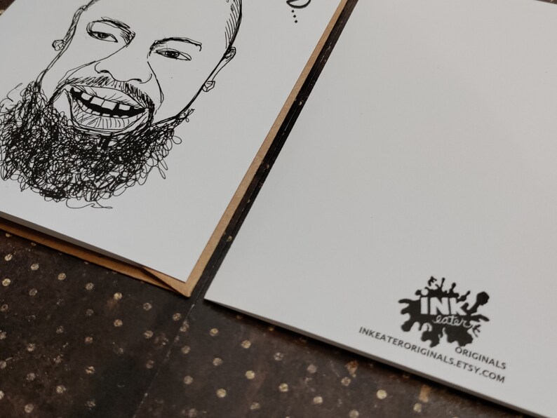 May include: Two greeting cards with a black and white line drawing of a smiling face with a beard. The cards are on a brown surface. One card has the drawing, the other has a logo that says "INK eater ORIGINALS INKEATERORIGINALS.ETSY.COM".
