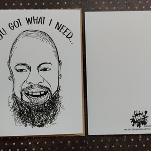 May include: A greeting card with a black and white line drawing of a smiling person with a beard. The text "YOU GOT WHAT I NEED..." is above the drawing. A blank card is next to it.