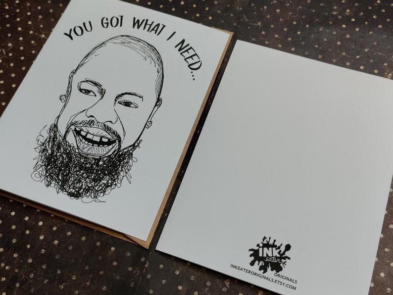 May include: Greeting card with a black and white sketch of a smiling person with a beard. The text "YOU GOT WHAT I NEED..." is above the face. The back of the card is blank with a logo and website address.